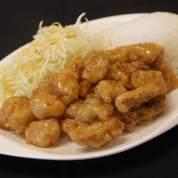 Niko Teriyaki's orange chicken, white rice, and shredded cabbage with dressing on a white plate.